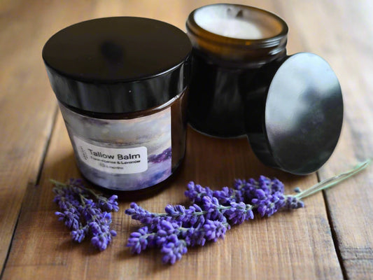 Two jars of Tallow Balm on a wooden table  surface with lavender flowers.